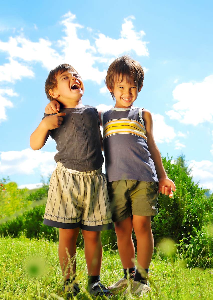bothers hug each other outdoors, smiling and laughing