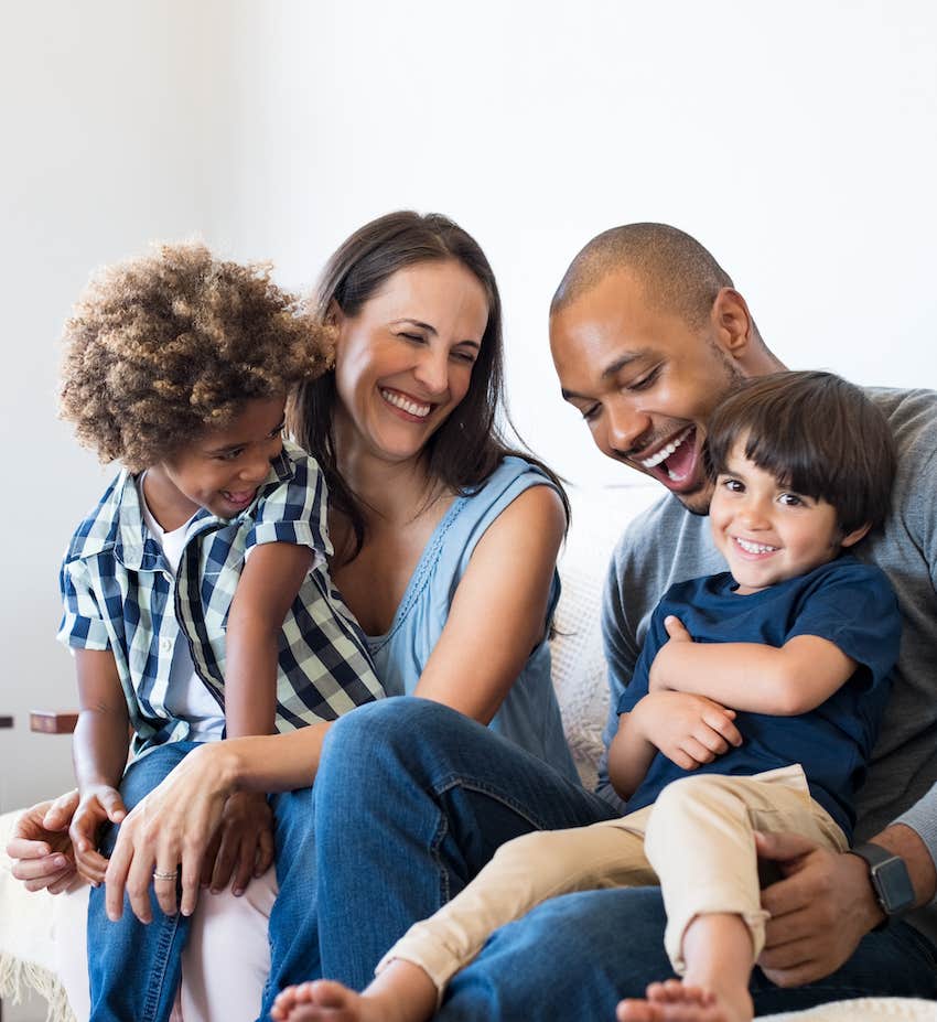 family sitting on sofa laughing together