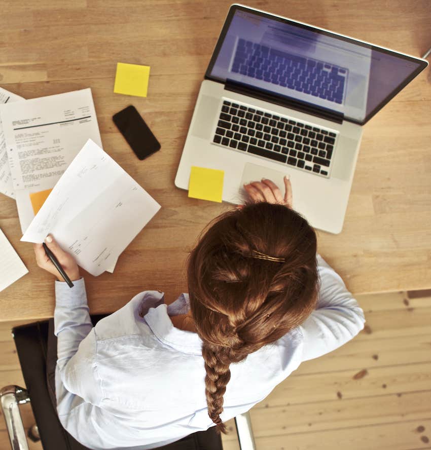 working at her office desk with documents and laptop